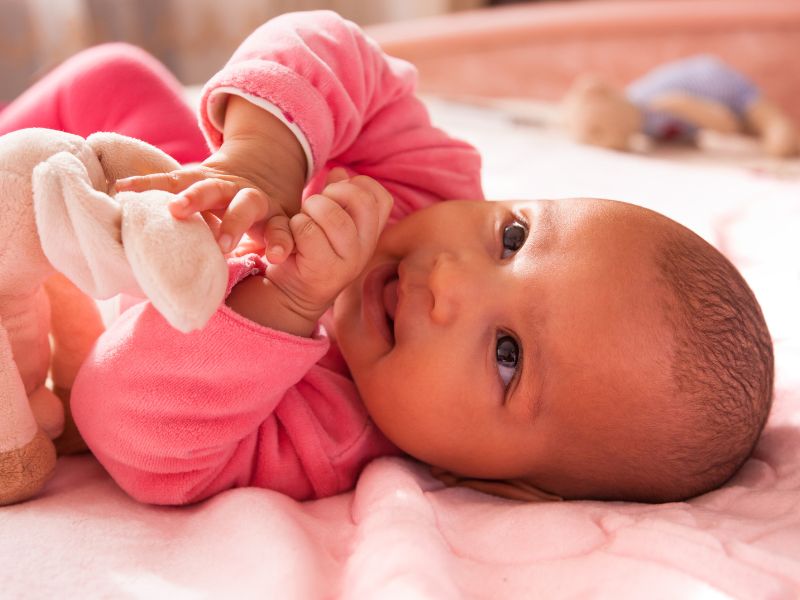 An infant playing on a soft mat in the Bright Stars infant room